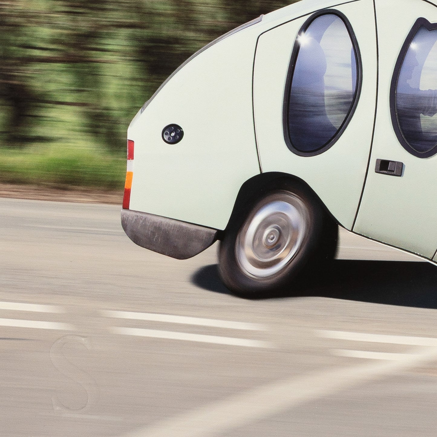 Light green car driving on a road with blurred background