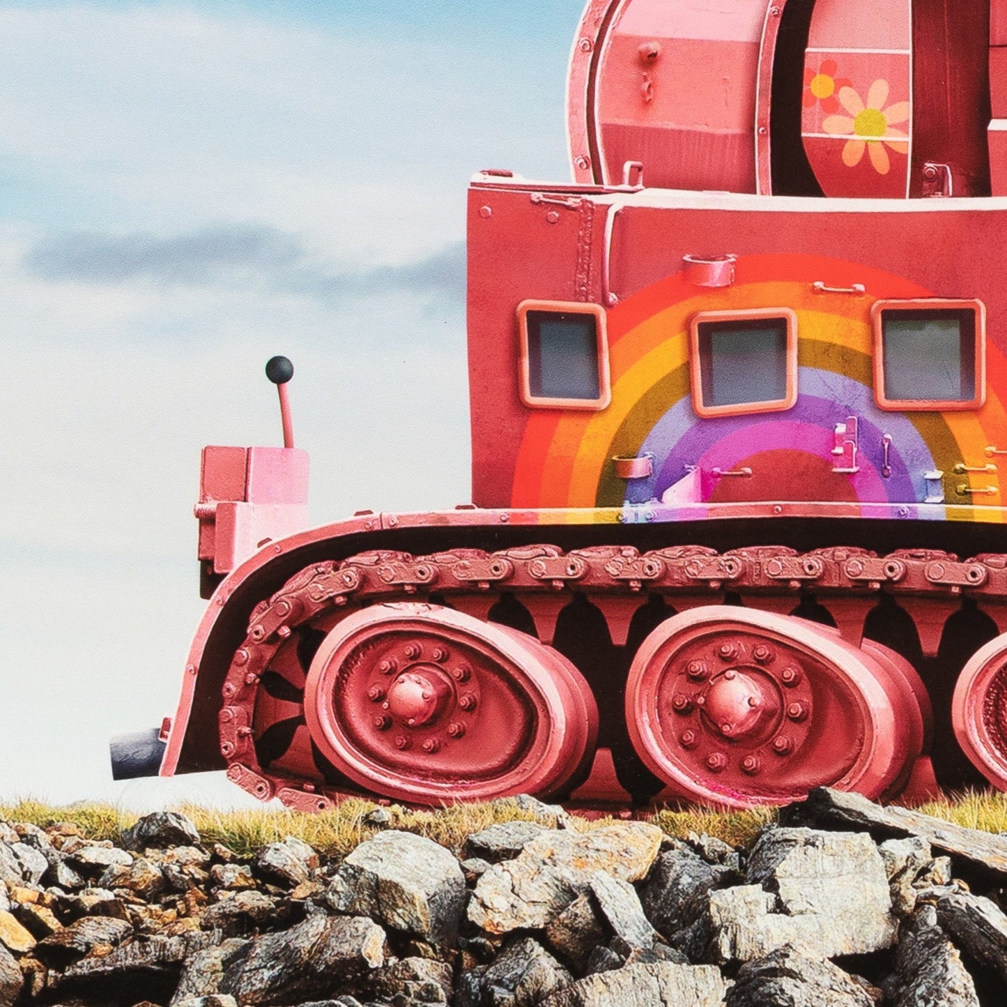 Colorful train car with a rainbow design on a rocky landscape